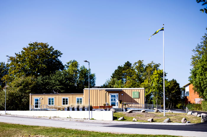 Yellow, wooden modular healthcare clinic surrounded by grass